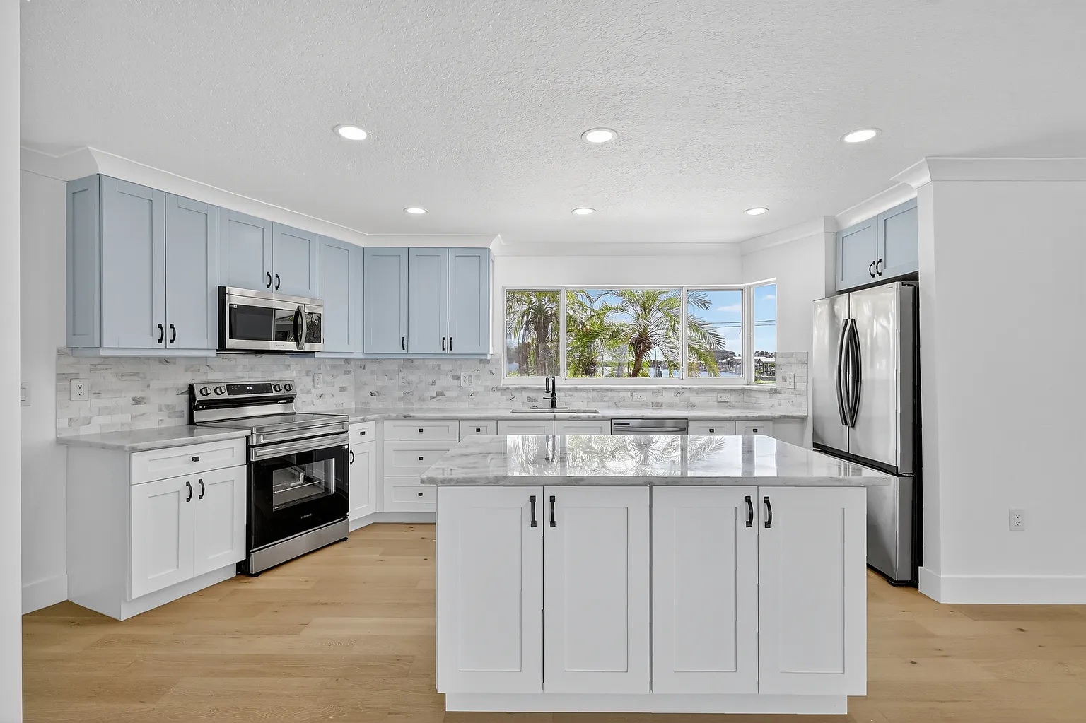 Custom shaker kitchen cabinet and marble-look tile backsplash installation with island in Clearwater Beach, FL