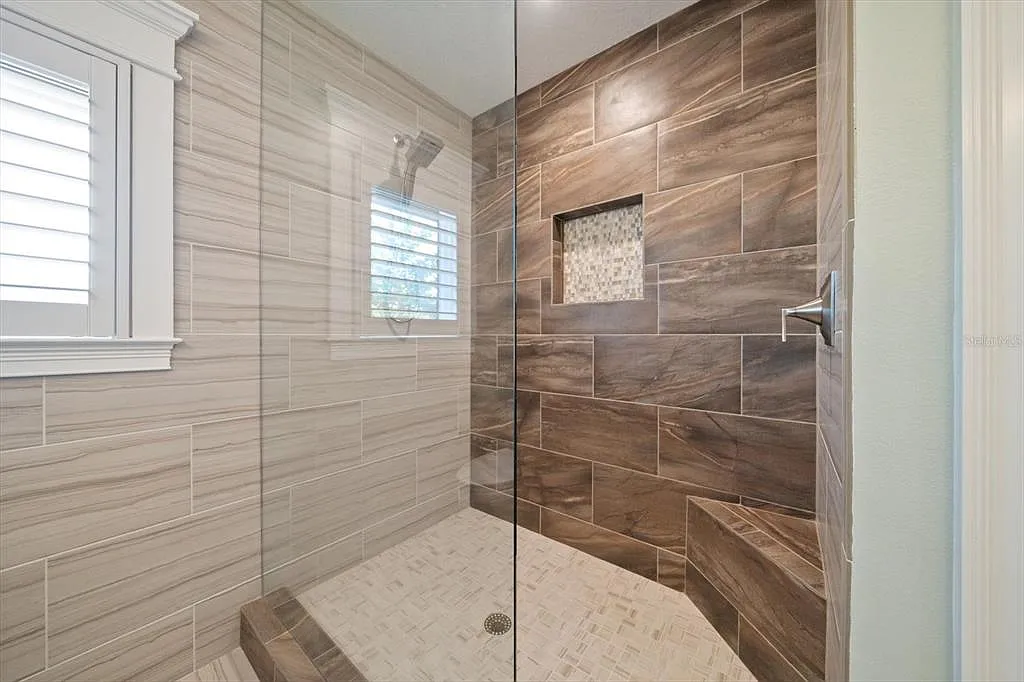 Walk-in shower with two-tone wood-look porcelain tile, mosaic floor and built-in bench in St. Pete Beach, FL